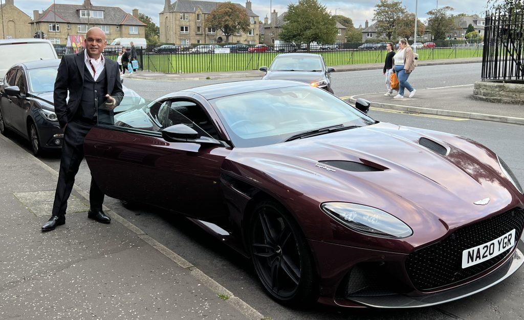 Shaf Rasul standing beside an Aston Martin DBS Superleggera