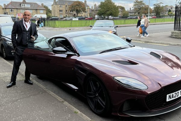 Shaf Rasul standing beside an Aston Martin DBS Superleggera
