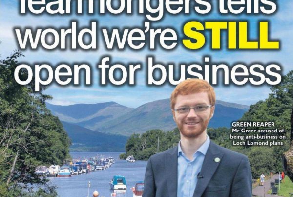 Headline graphic reading “Defeating kneejerk fearmongers tells world we’re STILL open for business” overlaid on a scenic image of Loch Lomond with calm waters, boats, and clear skies, symbolising investment potential.