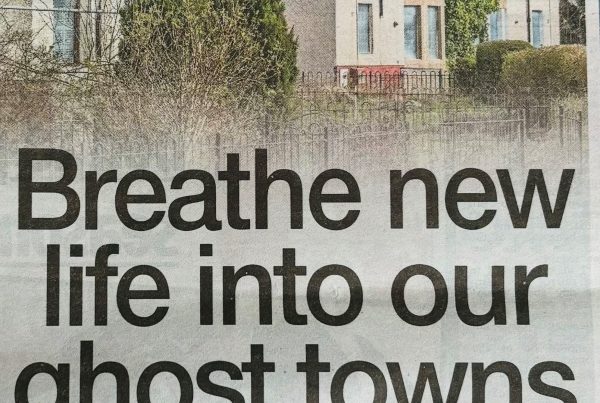 A row of boarded-up homes and shuttered shops in a quiet Scottish high street, overlaid with the text “Breathe new life into our ghost towns”.