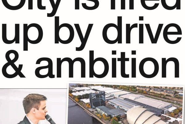 Shaf Rasul with a headline “City is Fired Up by Drive & Ambition” over an image of Glasgow’s skyline with the SEC and delegates entering a conference centre.