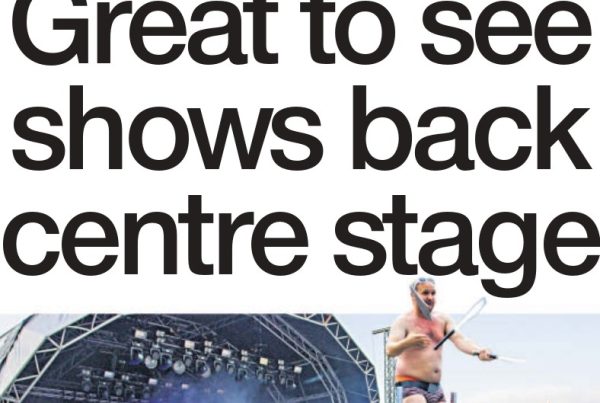 Crowds enjoying live music at a Scottish festival with stage lights beaming and the headline “Great to see shows back centre stage” in bold overlay.
