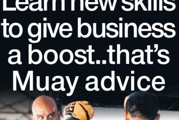 A focused businessperson practicing Muay Thai on a beach in Phuket, with sunrise and boxing gloves symbolising discipline, determination, and personal growth.