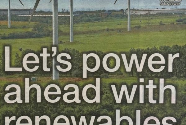A wind turbine and solar panel array in a green Scottish field with a sunrise in the background, overlaid with the text: “Let's power ahead with renewable”.