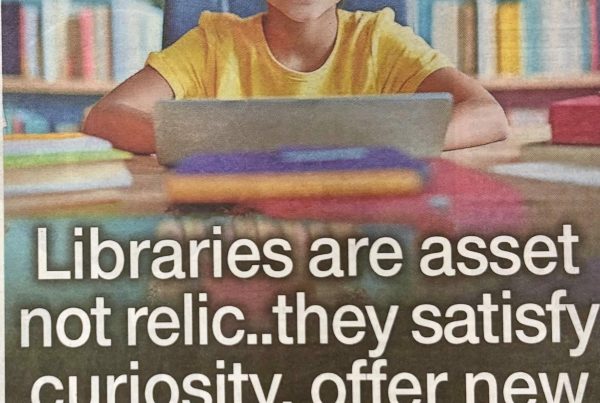 Headline graphic reading “Libraries are asset not relic…they satisfy curiosity, offer new skills & need saved” placed over an image of a smiling child in a library using a laptop