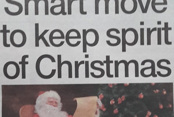Santa in a mask using a laptop, surrounded by Christmas lights and digital icons, with headline text “Smart move to keep spirit of Christmas” displayed boldly.