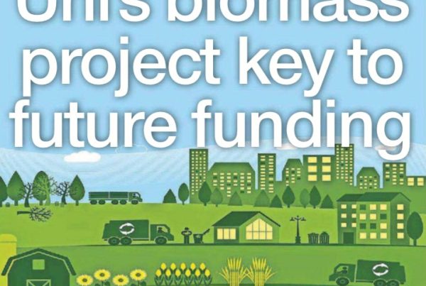 Banner showing the headline “Uni’s biomass project key to future funding” over a background of scientific lab equipment and glowing hydrogen elements.