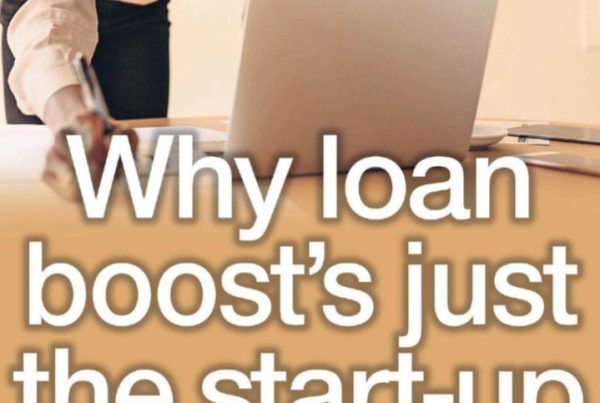 A hopeful Scottish entrepreneur holds a lightbulb in one hand and a signed Start-up Loan document in the other, standing confidently outside a small shop with a “New Business” sign.
