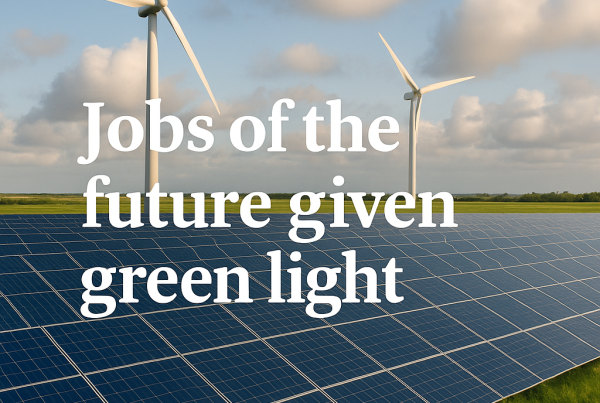 Wind turbines and solar panels under a partly cloudy sky with the headline "Jobs of the future given green light" overlaid in bold white text.