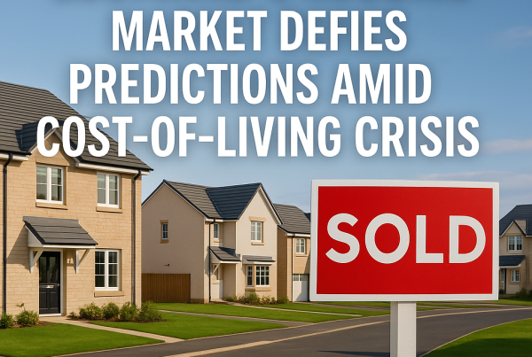 A wide shot of a suburban Scottish housing development under clear skies, showing a row of newly built homes with a "Sold" sign in the foreground. Bold white text over the image reads: "Scotland’s Housing Market Defies Predictions Amid Cost-of-Living Crisis."